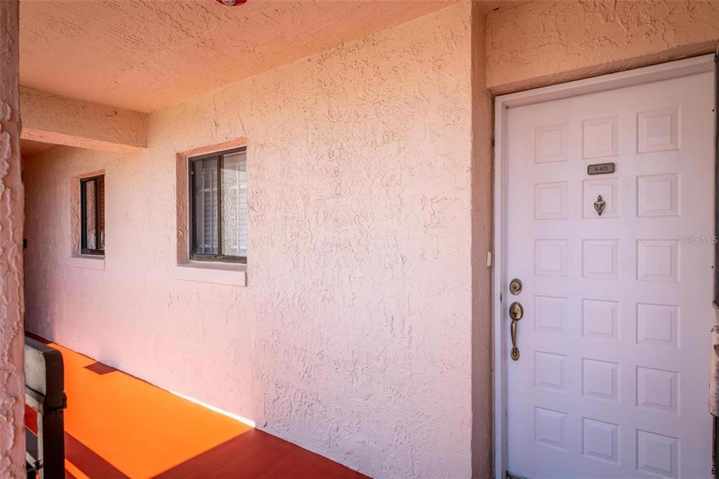 An exterior view of a building hallway featuring a white front door labeled 440 — 1162 CARMEL CIRCLE UNIT 440, CASSELBERRY, FL
