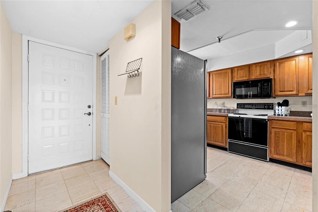 An entryway with a white door leads into a kitchen featuring wood cabinets and appliances — 1162 CARMEL CIRCLE UNIT 440, CASSELBERRY, FL