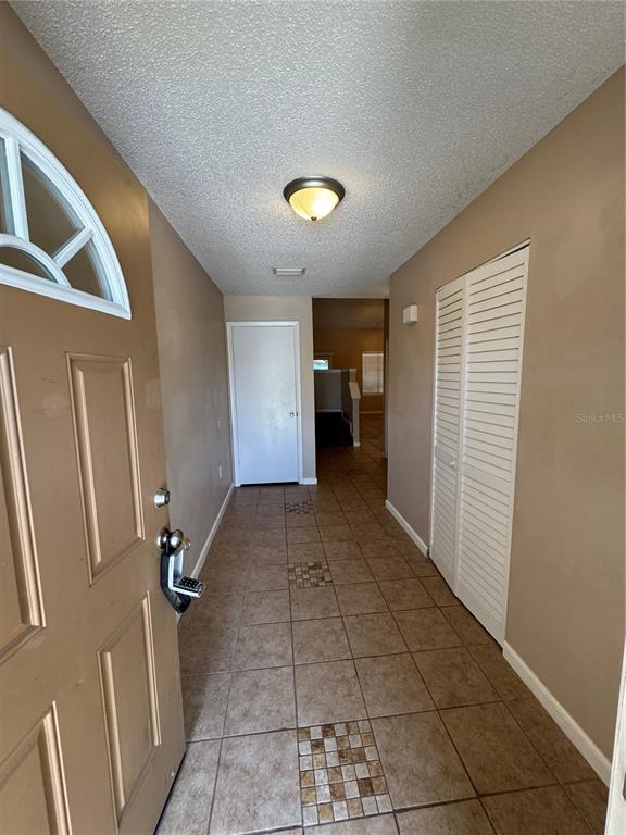 An entryway features tan tile flooring with decorative accents, a white closet, and a door — 967 STUCKI TERRACE, WINTER GARDEN, FL