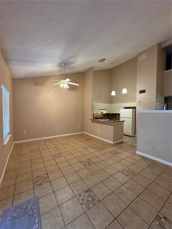 An open-concept room features a tiled floor, a ceiling fan, and an adjacent kitchen area — 967 STUCKI TERRACE, WINTER GARDEN, FL