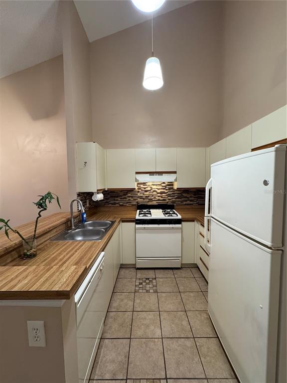 A kitchen features white appliances, wood countertops, a tiled backsplash, and light-colored cabinets — 967 STUCKI TERRACE, WINTER GARDEN, FL