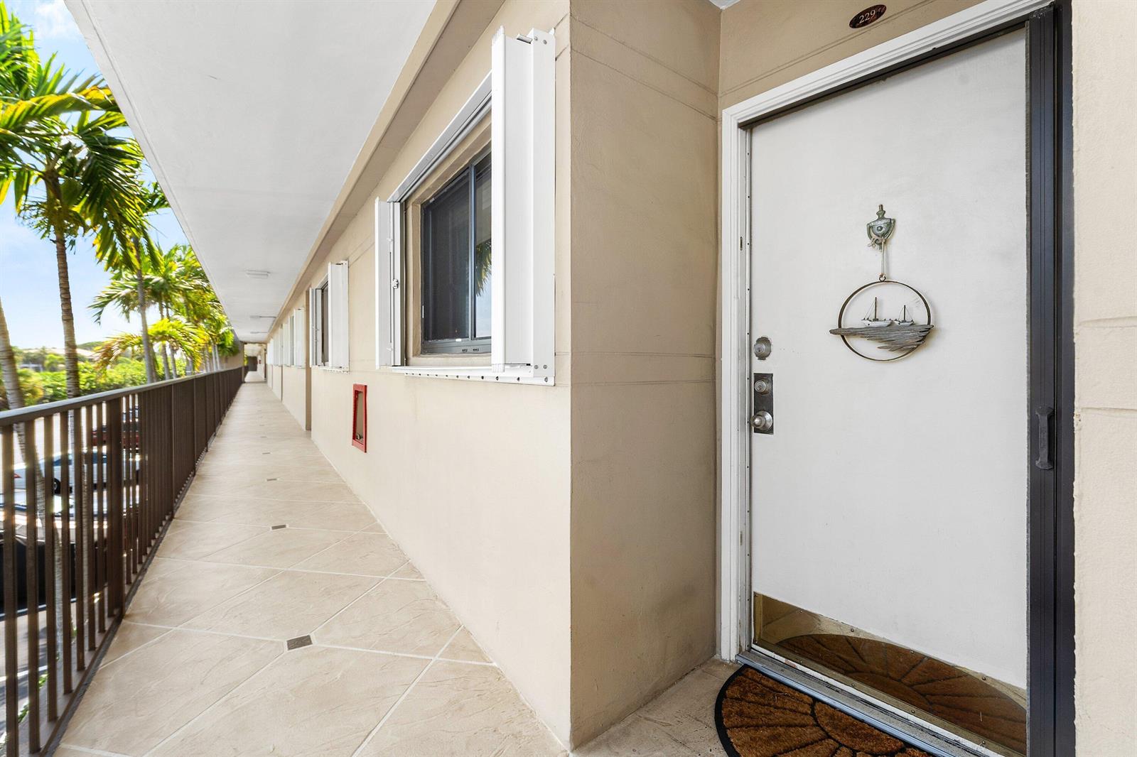 An exterior walkway with a white door, a window, and a metal railing — 3605 S Ocean Boulevard, South Palm Beach FL 33480, SOUTH PALM BEACH, FL