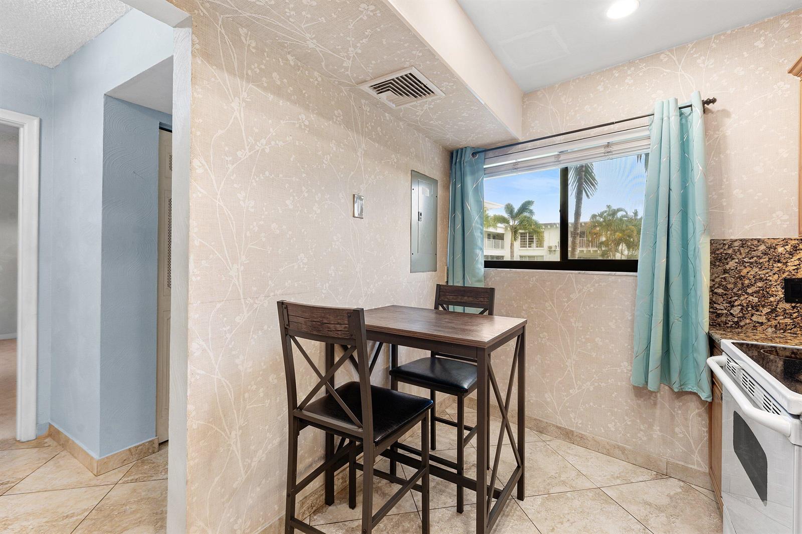 A small dining area features a table with two chairs, patterned wallpaper, and tiled floors — 3605 S Ocean Boulevard, South Palm Beach FL 33480, SOUTH PALM BEACH, FL