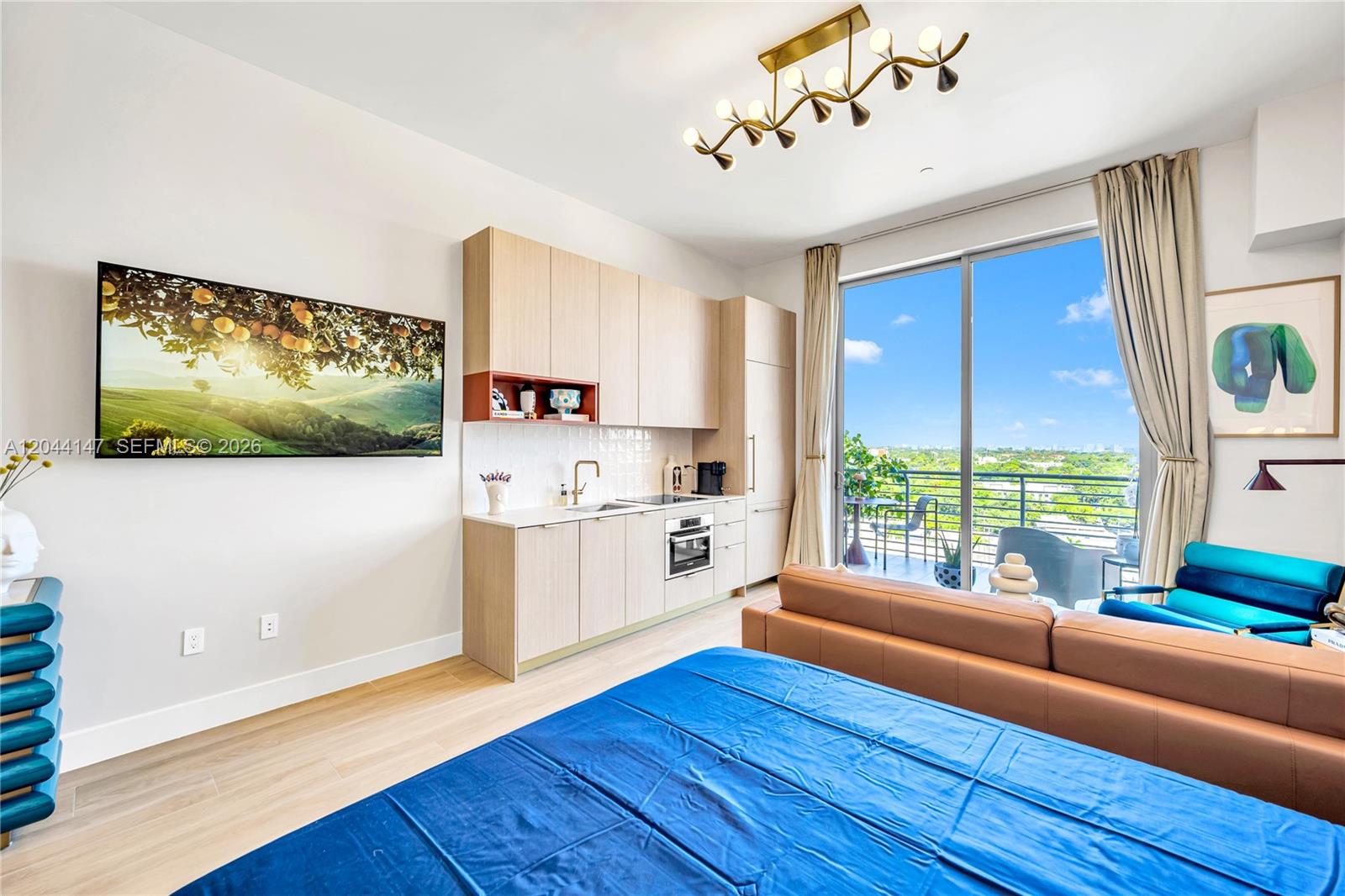 A studio apartment features a kitchenette, a bed, a sofa, and a balcony with views — 90 NE 32nd, Miami FL 33127, MIAMI, FL