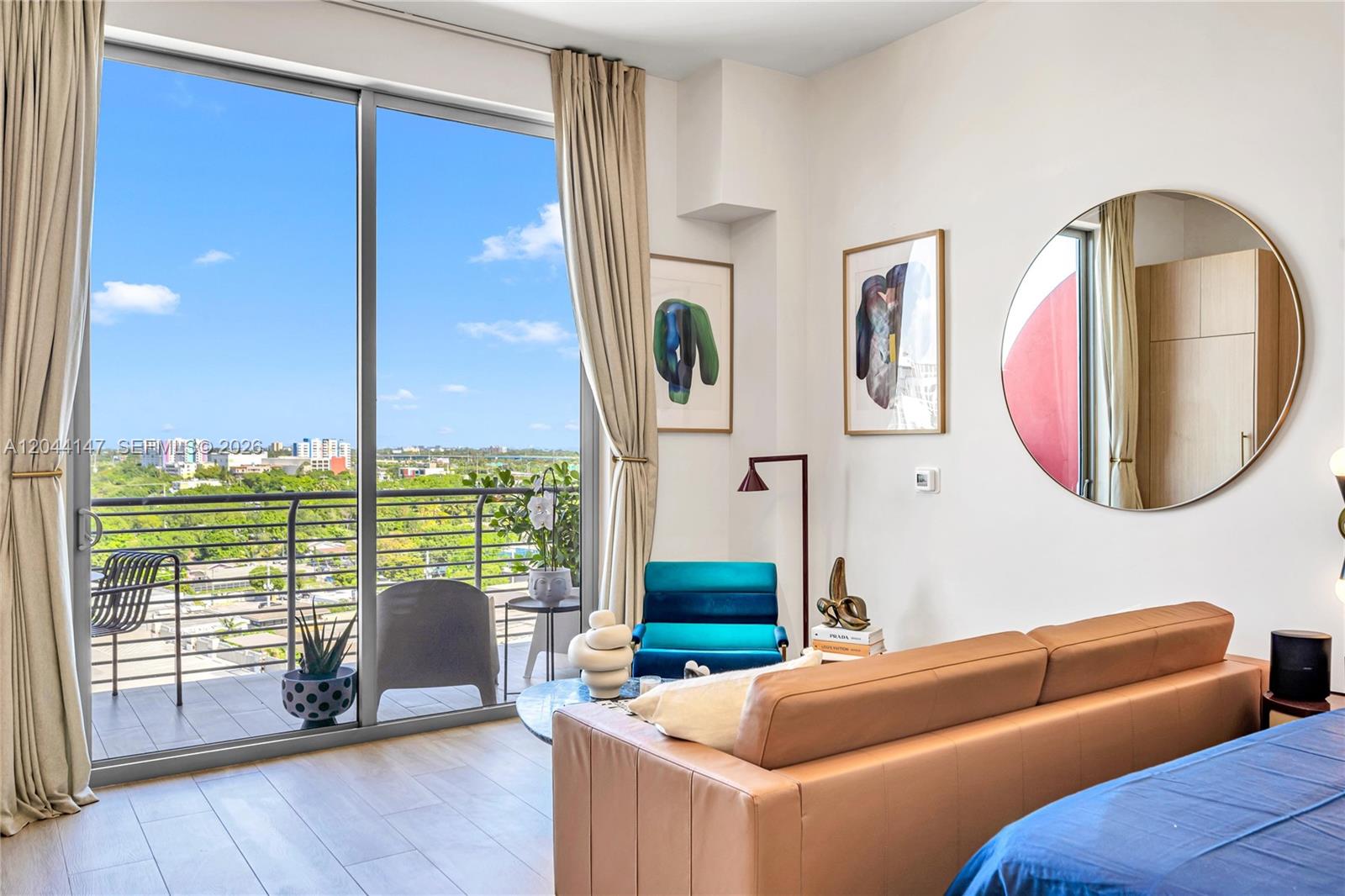 A modern bedroom features a tan sofa, a blue accent chair, and a balcony view — 90 NE 32nd, Miami FL 33127, MIAMI, FL