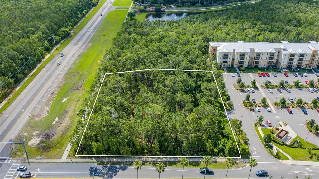 An aerial view shows a rectangular, wooded plot of land bordered by roads and buildings — 1500 TOWN WEST BOULEVARD, PORT ORANGE, FL