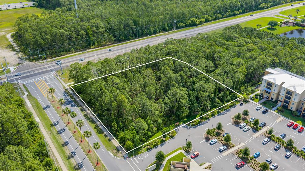 An aerial view shows a rectangular, wooded vacant lot bordered by a road and parking lot — 1500 TOWN WEST BOULEVARD, PORT ORANGE, FL