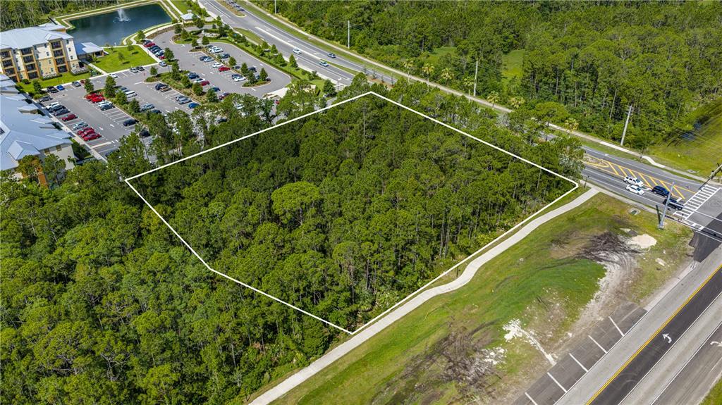 An aerial view shows a wooded, rectangular plot of land bordered by roads and buildings — 1500 TOWN WEST BOULEVARD, PORT ORANGE, FL