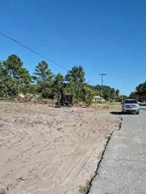 An excavator sits on a cleared, sandy lot next to a paved road and vehicle — 0 S JACKSON STREET, LAKE WALES, FL