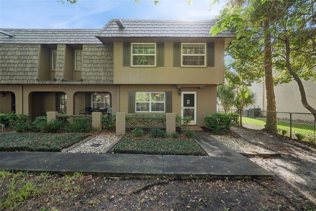 A two-story townhouse exterior with brown siding, a shingled roof, and a small front patio — 3104 HARRISON AVENUE UNIT 33, ORLANDO, FL