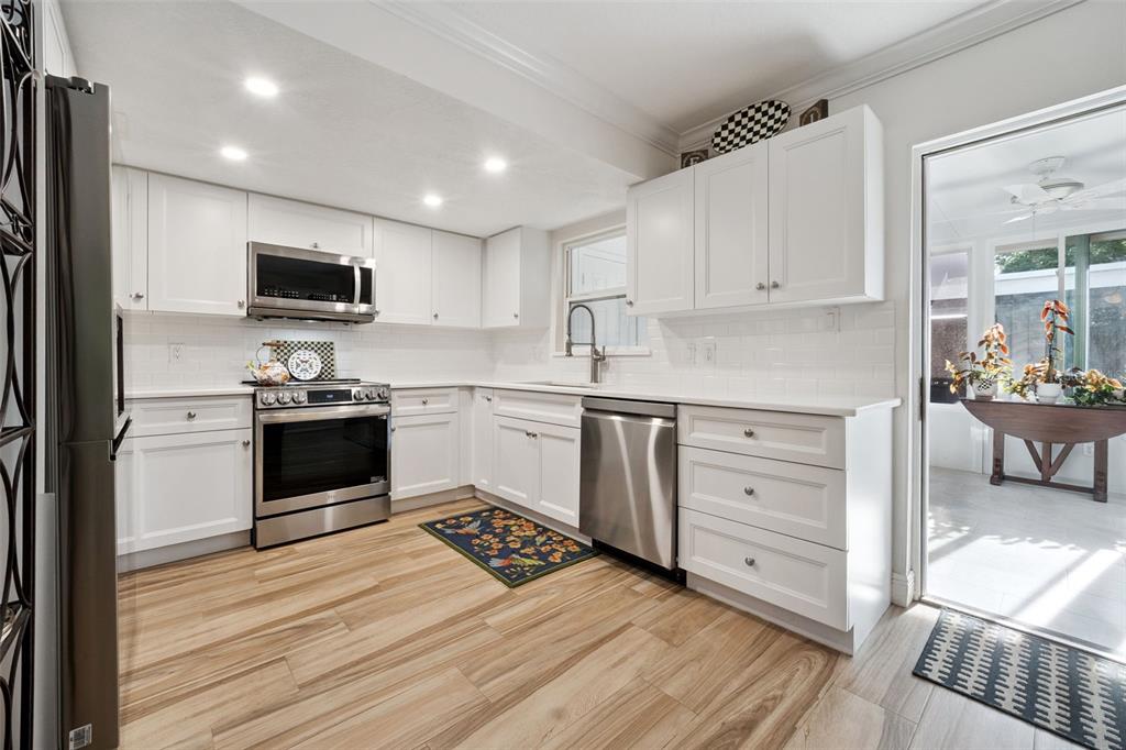 A kitchen with white cabinets, stainless steel appliances, subway tile backsplash, and wood-look flooring — 3104 HARRISON AVENUE UNIT 33, ORLANDO, FL