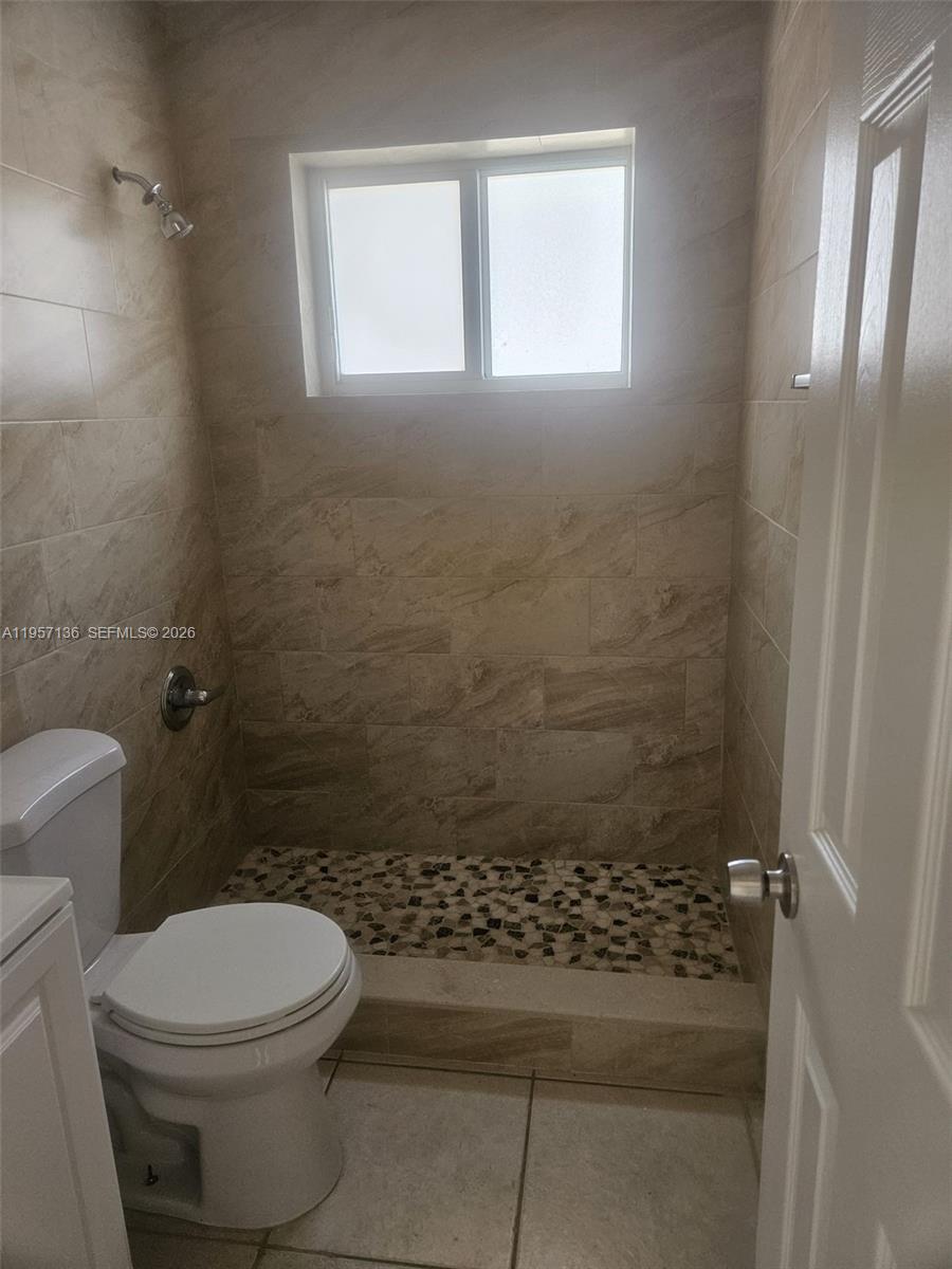 A bathroom features a walk-in shower with pebble flooring and beige wall tiles — 2230 Madison St # 01, Hollywood FL 33020, HOLLYWOOD, FL