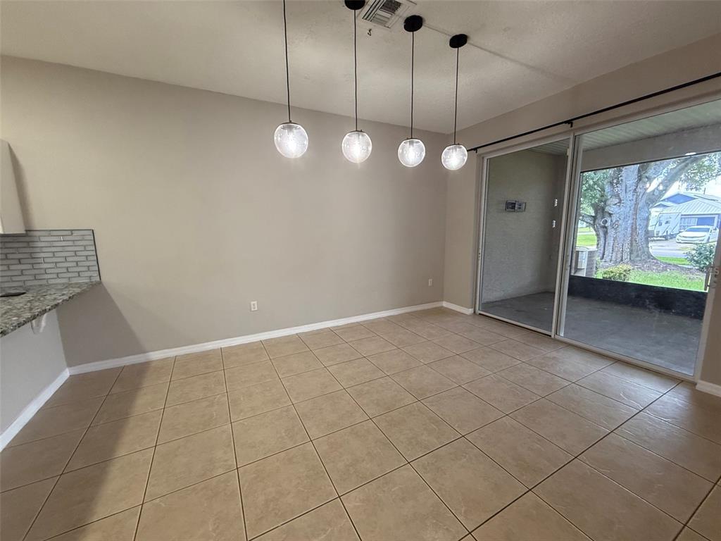An empty dining area features tile flooring, four pendant lights, and a sliding glass door — 3421 HOME TOWN LANE, ST CLOUD, FL