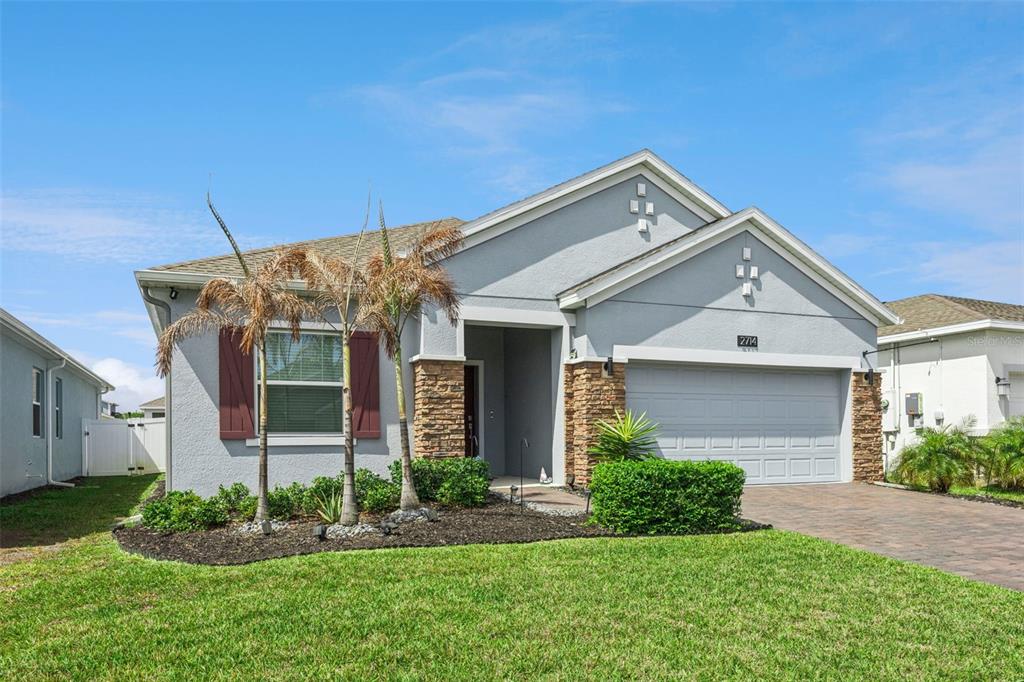A single-story house with a gray stucco exterior, stone accents, and a two-car garage — 2714 SLASH WAY, ST CLOUD, FL