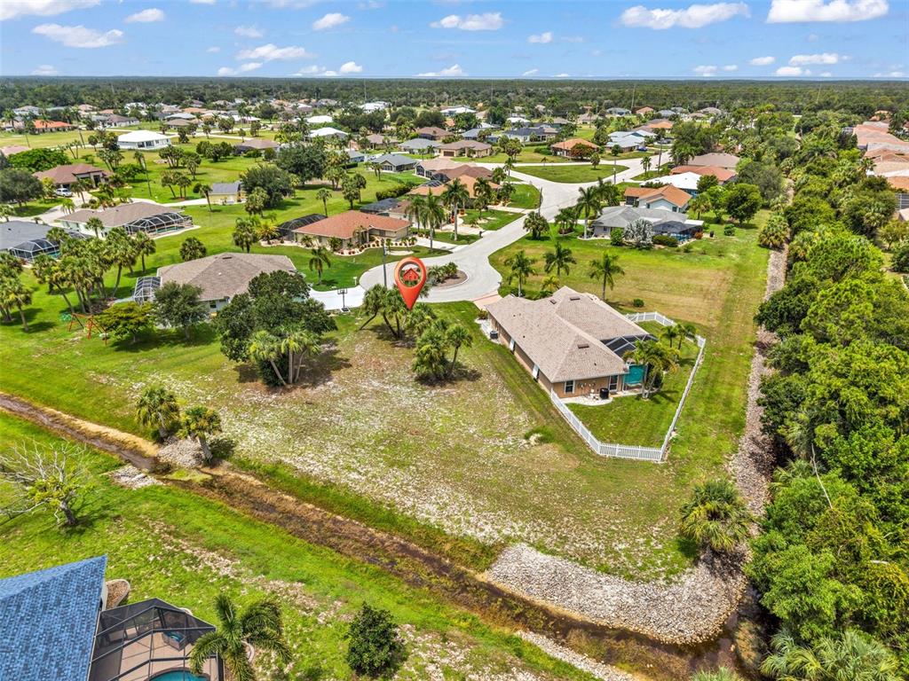 An aerial view shows a residential lot with a house and a drainage canal — 604 TRUMPET TREE, PUNTA GORDA, FL