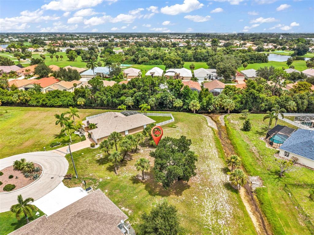 An aerial view shows a residential lot with trees and a house near a canal — 604 TRUMPET TREE, PUNTA GORDA, FL