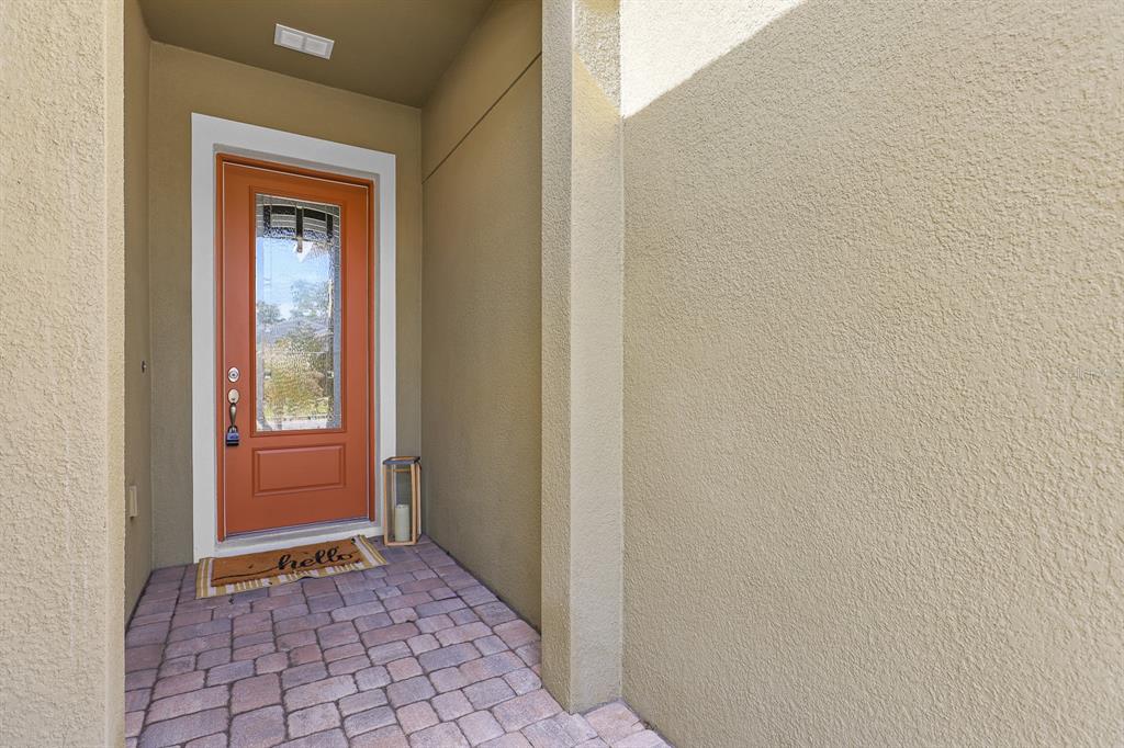 A front entryway features a bright orange door with a glass panel and a doormat — 13930 NATURES RESERVE DRIVE, LITHIA, FL