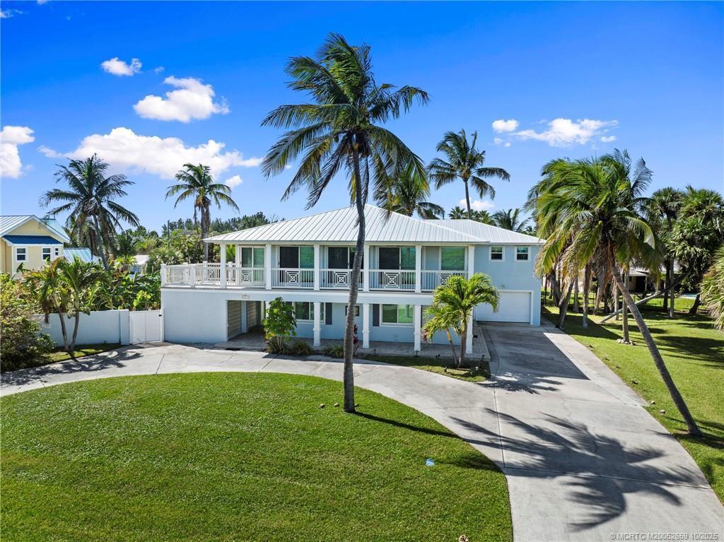 A two-story light blue house with a metal roof and a wrap-around balcony — 1911 Surfside Drive, Fort Pierce FL 34949, FORT PIERCE, FL