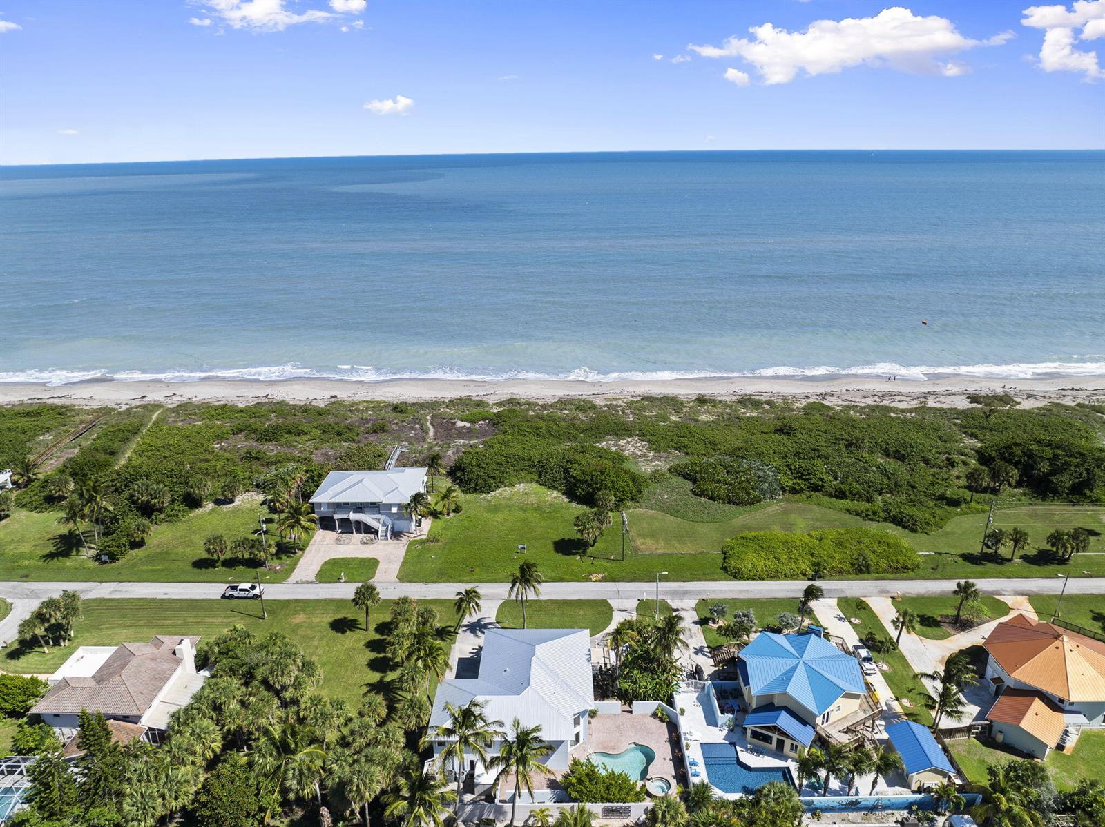 An aerial view shows several houses near a beach with a blue ocean — 1911 Surfside Drive, Fort Pierce FL 34949, FORT PIERCE, FL