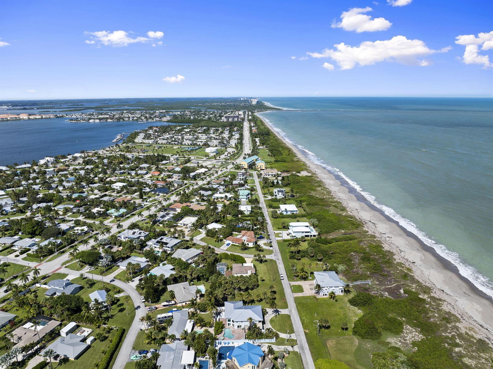 An aerial view shows a coastal neighborhood with houses situated between a bay and the ocean — 1911 Surfside Drive, Fort Pierce FL 34949, FORT PIERCE, FL