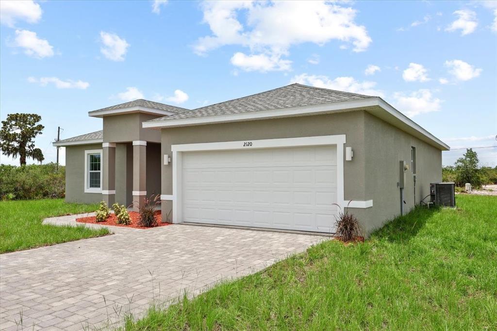 A single-story house with a beige stucco exterior, a two-car garage, and a paver driveway — 2120 POINCIANA DRIVE, INDIAN LAKE ESTATES, FL