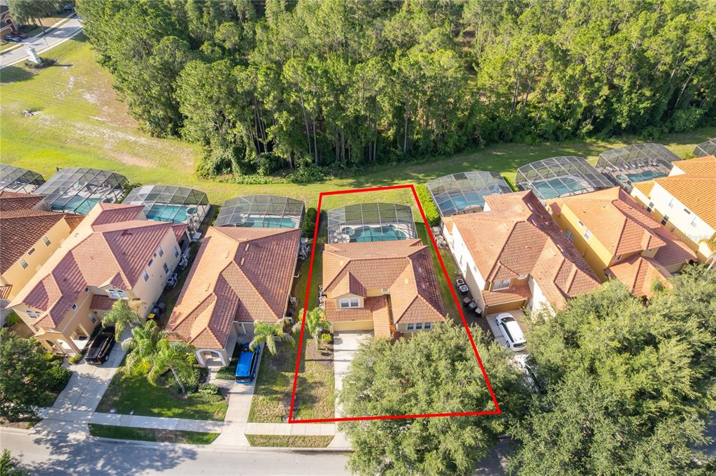 An aerial view shows a residential house with a tiled roof and a screened pool — 385 ORANGE COSMOS BOULEVARD, DAVENPORT, FL