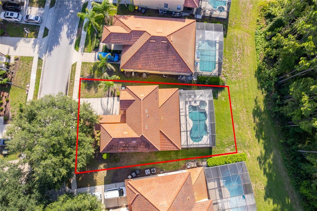 An aerial view shows a house with a tiled roof, pool enclosure, and fenced yard — 385 ORANGE COSMOS BOULEVARD, DAVENPORT, FL