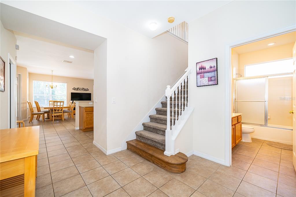A tiled entryway features a carpeted staircase with a white railing and an adjacent bathroom — 385 ORANGE COSMOS BOULEVARD, DAVENPORT, FL