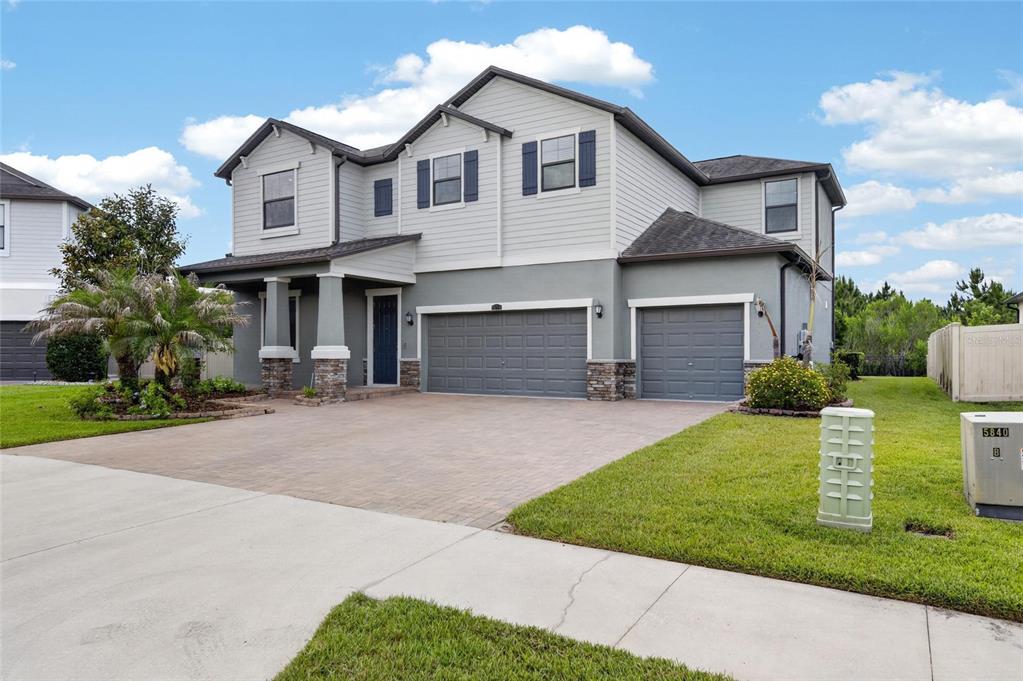 A two-story house with a gray exterior, stone accents, and a three-car garage — 2905 HILLIARD DRIVE, WESLEY CHAPEL, FL