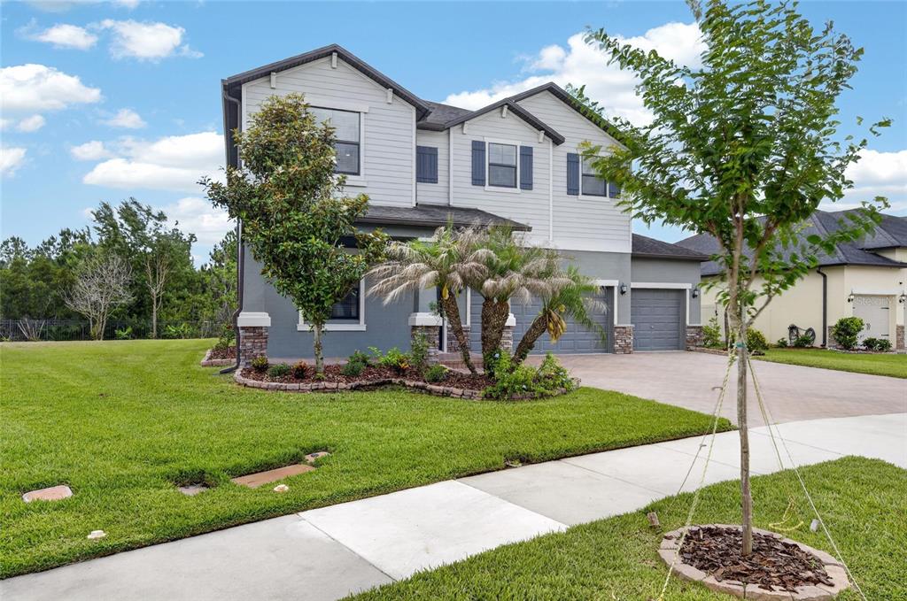 A two-story house with gray siding, a stone-accented facade, and a three-car garage — 2905 HILLIARD DRIVE, WESLEY CHAPEL, FL