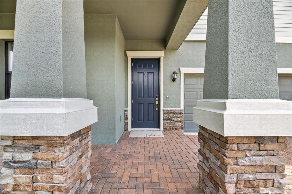 A covered front porch with stone-based columns leads to a dark blue front door — 2905 HILLIARD DRIVE, WESLEY CHAPEL, FL