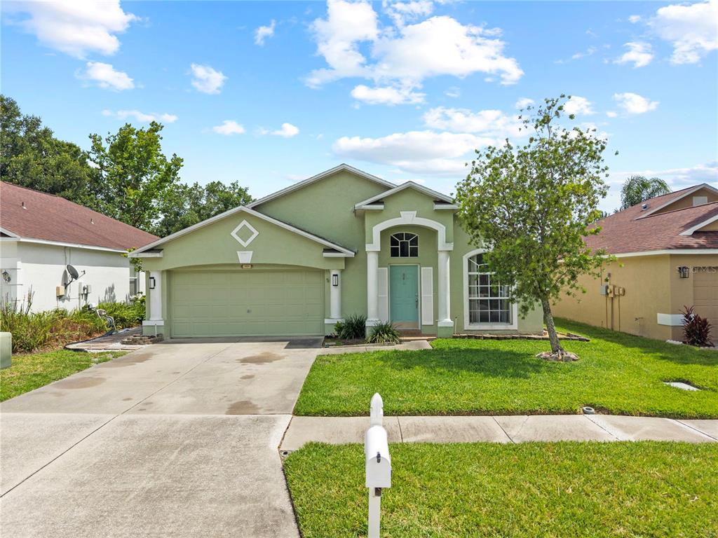 A single-story green house with a two-car garage and a front lawn under a sky — 25237 SEVEN RIVERS CIRCLE, LAND O LAKES, FL