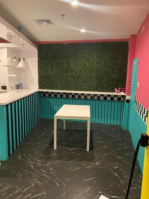 A room with a green hedge wall, teal vertical slats, and black marble-patterned tile flooring — 88 CALLE REINA ST, PONCE, PR