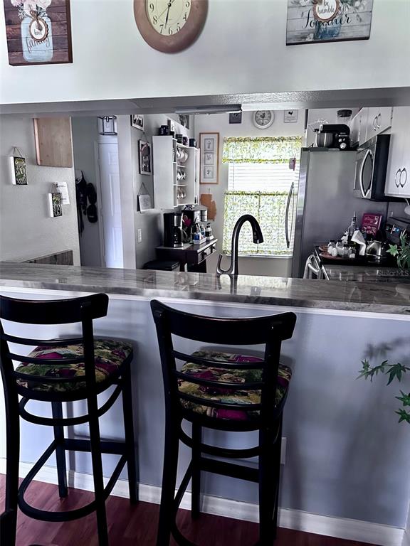 A kitchen with a breakfast bar, two dark wooden stools, and stainless steel appliances — 6211 BAYSIDE KEY DRIVE, TAMPA, FL