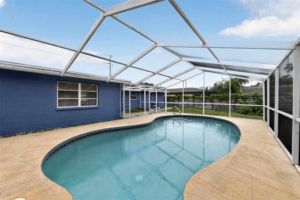 A blue house with a screened-in pool and patio area under a white frame enclosure — 3238 SAVAGE ROAD, SARASOTA, FL