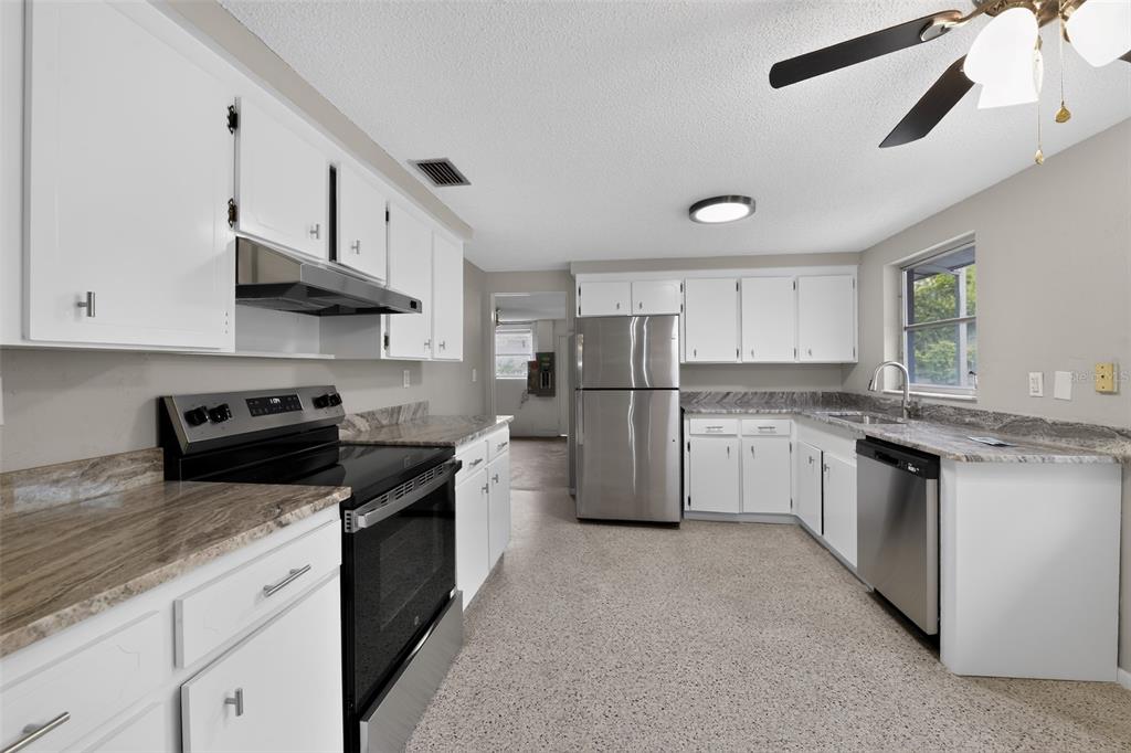 A kitchen with white cabinets, stainless steel appliances, granite countertops, and light-colored speckled flooring — 3238 SAVAGE ROAD, SARASOTA, FL