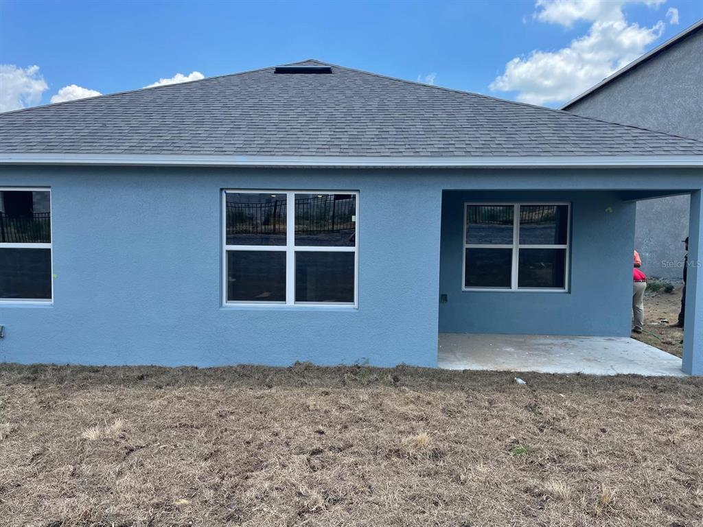 The exterior rear view of a blue house shows a covered patio and three windows — 2015 CHICKASAW BOULEVARD, DAVENPORT, FL