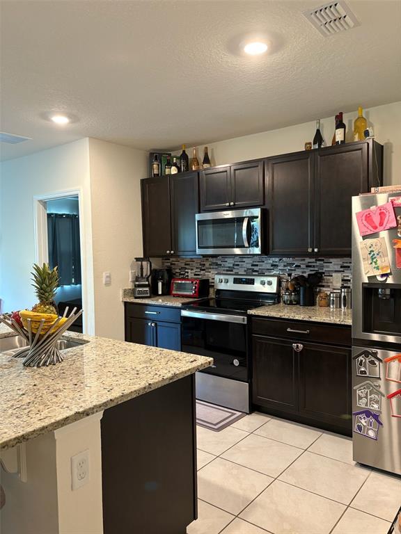 A kitchen features dark wood cabinets, granite countertops, stainless steel appliances, and a center island — 2015 CHICKASAW BOULEVARD, DAVENPORT, FL