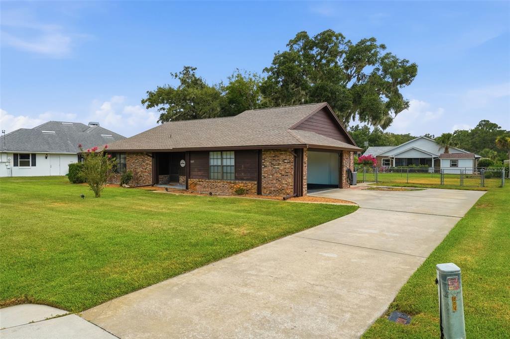 A single-story brick house with a brown shingled roof and an attached garage — 1805 VIRGINIA COURT, TAVARES, FL