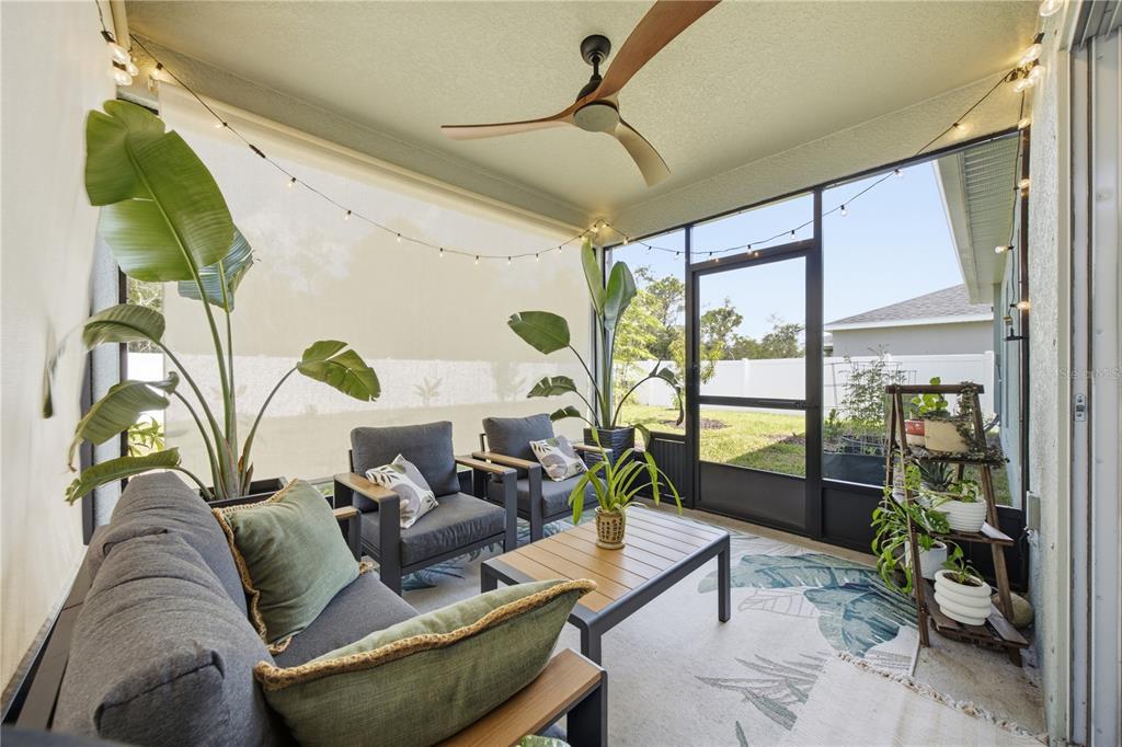 A screened-in patio features gray outdoor furniture, a ceiling fan, and string lights — 822 170TH COURT E, BRADENTON, FL