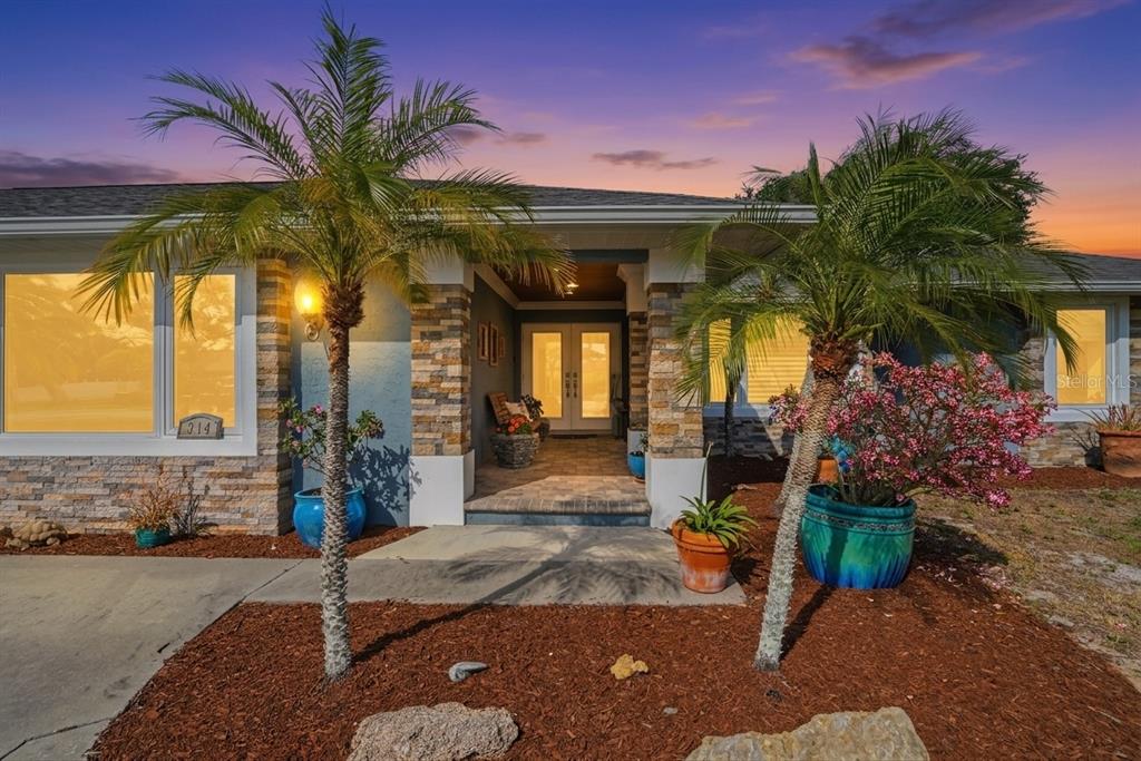 The exterior of a single-story house features stone accents, palm trees, and a covered entryway — 314 S SHORE DRIVE, OSPREY, FL