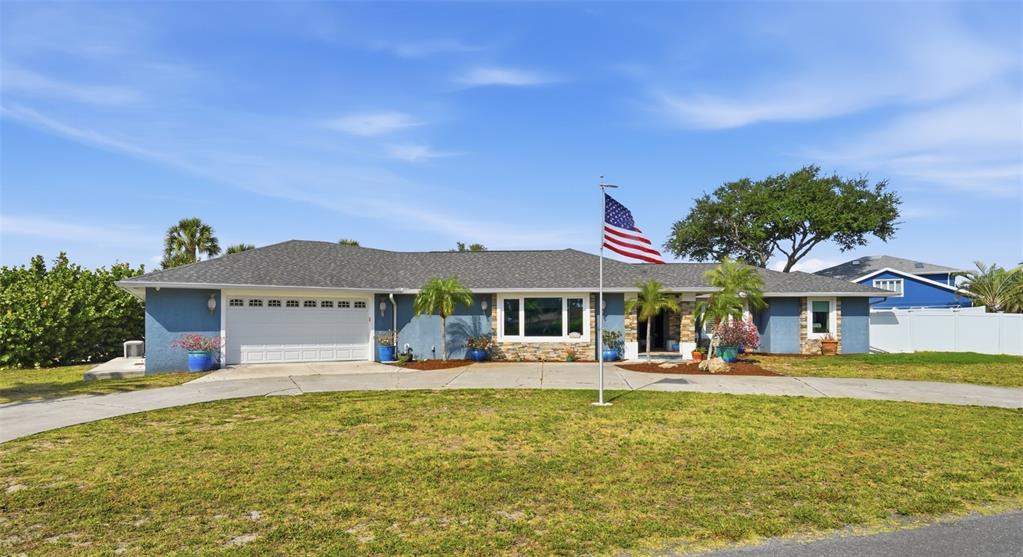 A single-story blue house with a white garage door and an American flag out front — 314 S SHORE DRIVE, OSPREY, FL