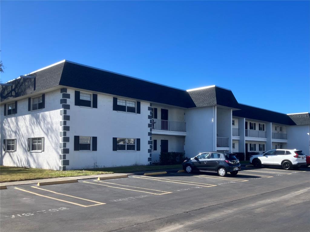 A two-story apartment building with white stucco walls, dark trim, and a parking lot — 202 47TH AVENUE DRIVE W UNIT 332, BRADENTON, FL