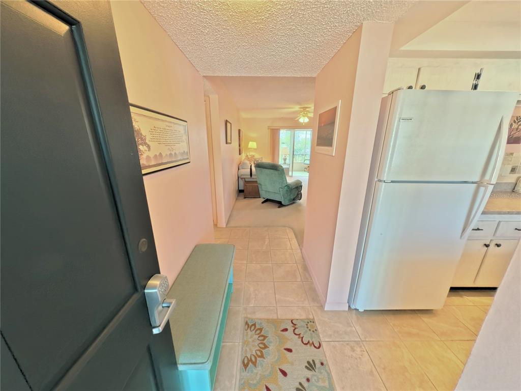 An entryway with tile flooring leads into a living area with a light blue recliner — 202 47TH AVENUE DRIVE W UNIT 332, BRADENTON, FL