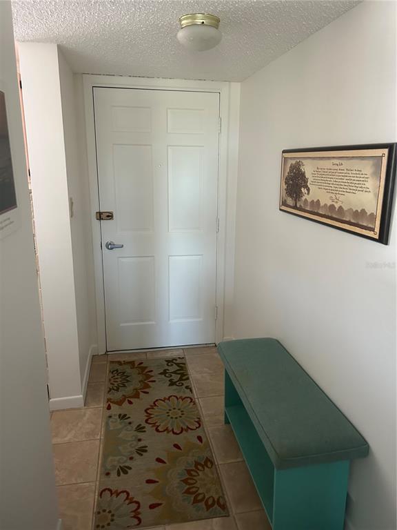 An entryway features a white door, a teal bench, and a patterned rug on tile — 202 47TH AVENUE DRIVE W UNIT 332, BRADENTON, FL