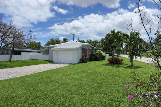 A single-story house with a white garage and gravel driveway sits on a grassy lot — 1107 S 15th Avenue, Hollywood FL 33020, HOLLYWOOD, FL
