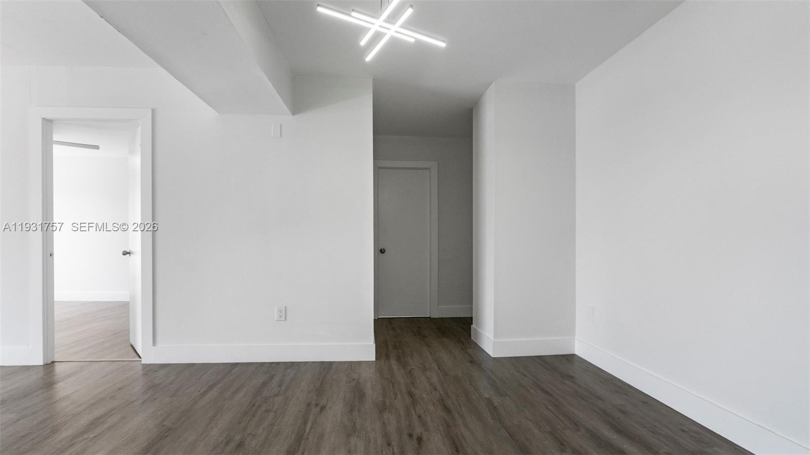 A room with white walls, dark wood-look flooring, and a modern geometric ceiling light — 4158 Inverrary Dr # 409, Lauderhill FL 33319, LAUDERHILL, FL