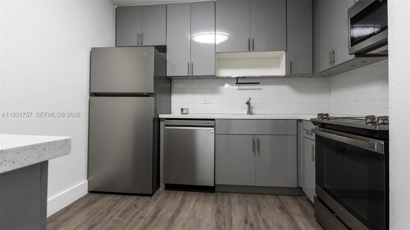 A kitchen features gray cabinets, stainless steel appliances, and a white subway tile backsplash — 4158 Inverrary Dr # 409, Lauderhill FL 33319, LAUDERHILL, FL