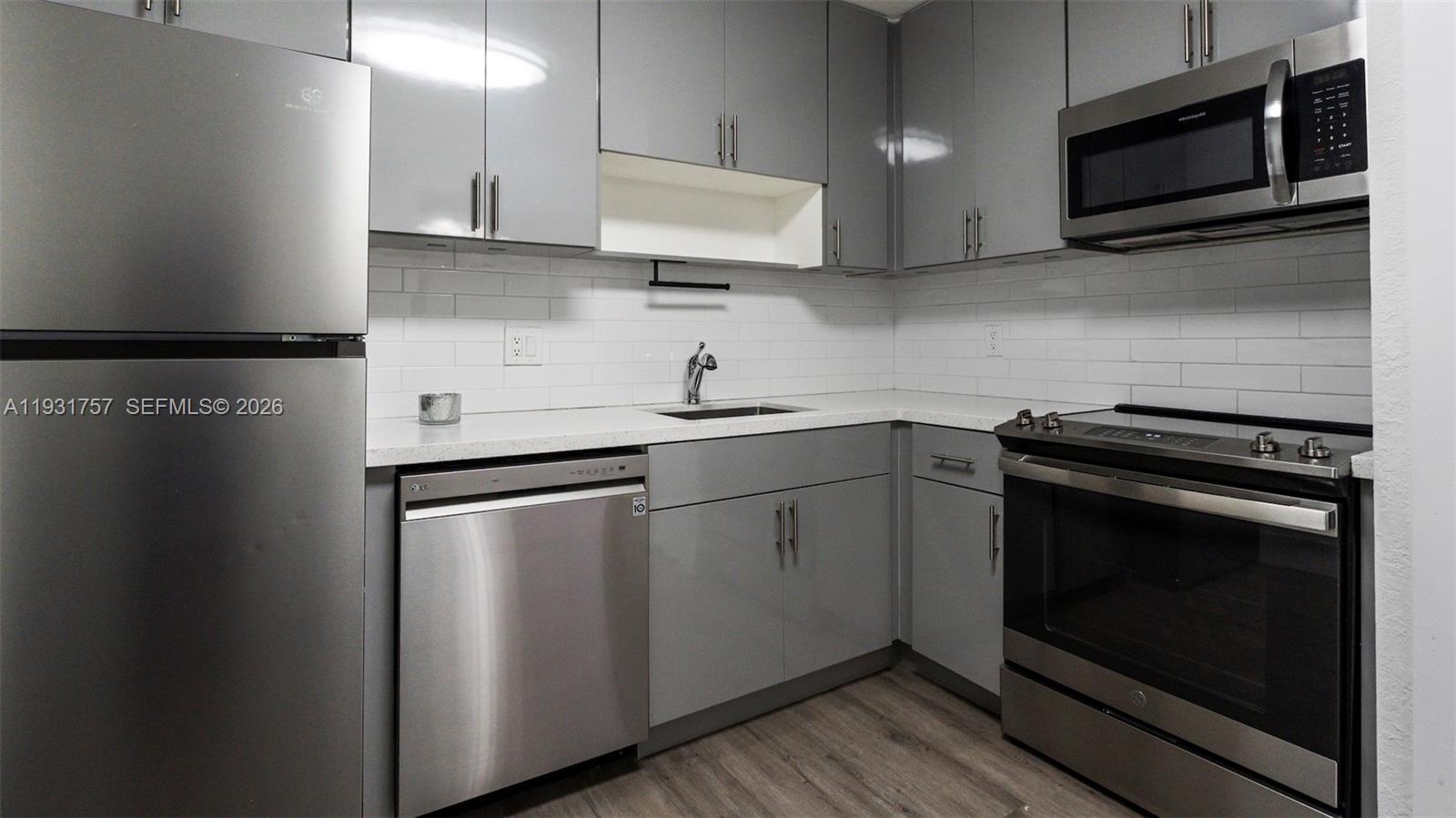 A modern kitchen features gray cabinets, stainless steel appliances, and a white subway tile backsplash — 4158 Inverrary Dr # 409, Lauderhill FL 33319, LAUDERHILL, FL