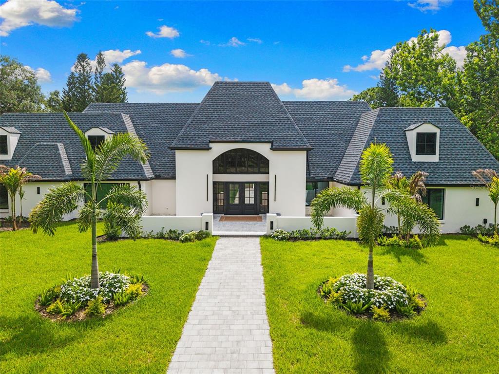 A white house with a dark shingled roof and a stone walkway leading to the entrance — 7351 IGUANA DRIVE, SARASOTA, FL